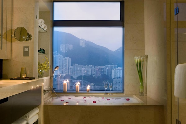 Une salle de bain avec une baignoire, des bougies et une vue sur la ville.