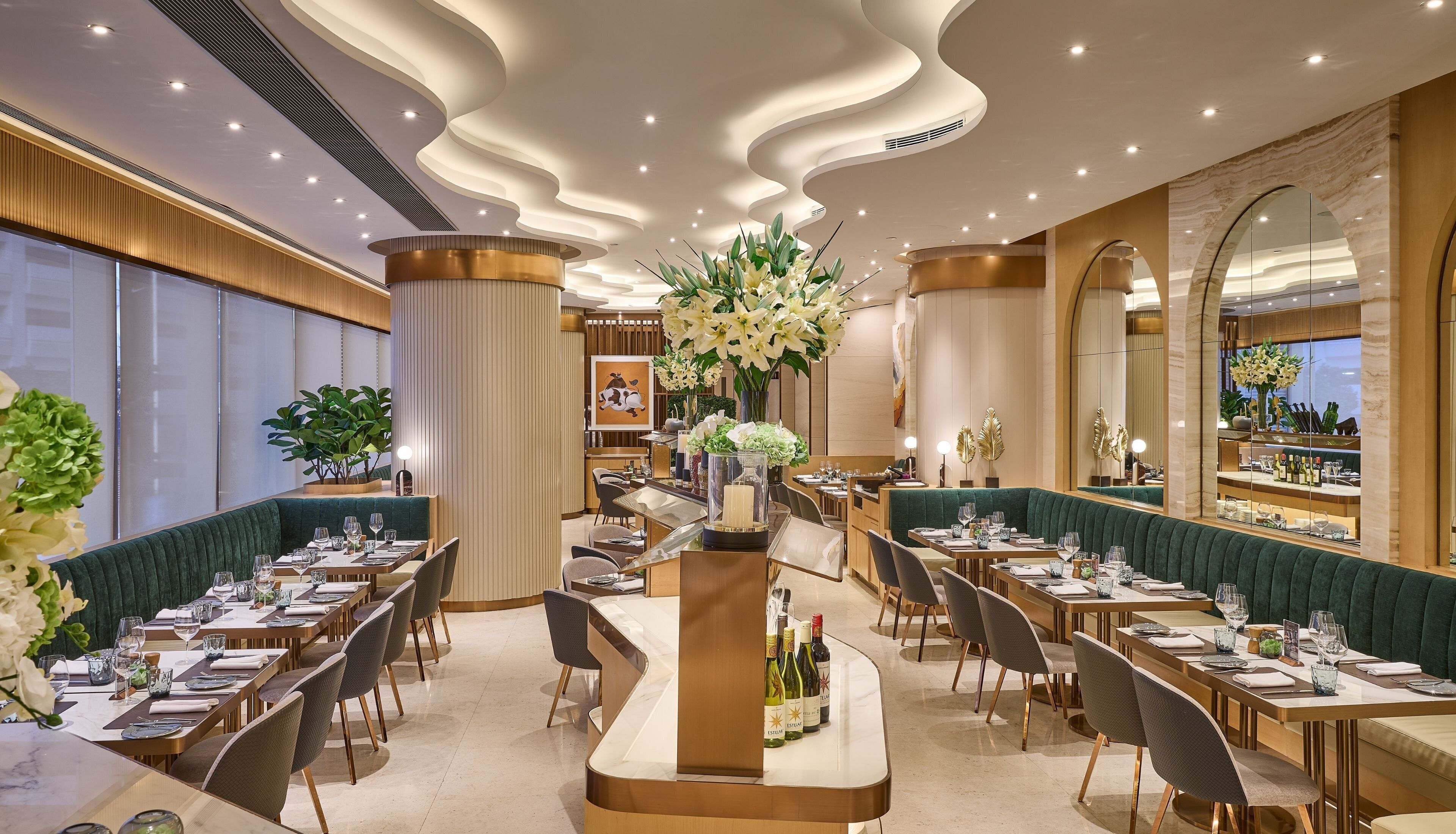 A restaurant with a central island, multiple dining tables, and green upholstered booths.
