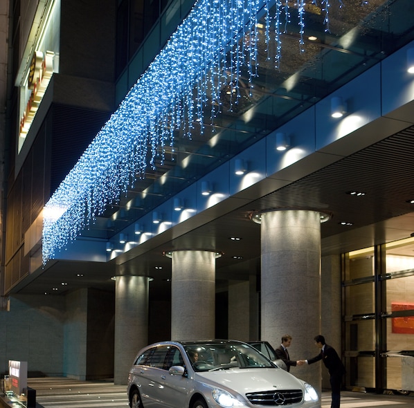 Un edificio moderno con fachada de vidrio y un coche estacionado frente a él.
