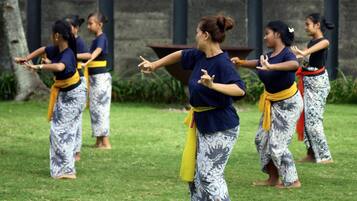 A group of people practicing martial arts outdoors on a grassy area with a stone wall in the background.