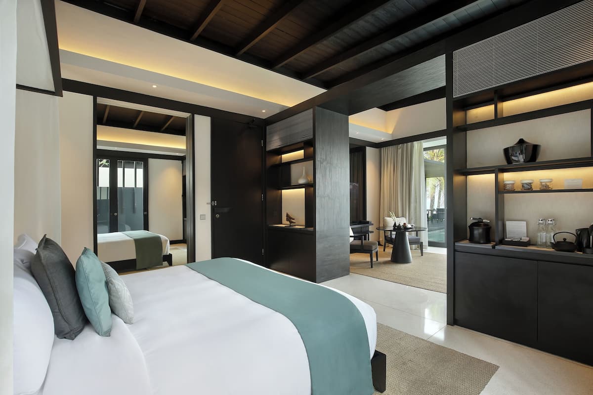 A modern hotel room with a large bed, a desk, and a kitchenette.