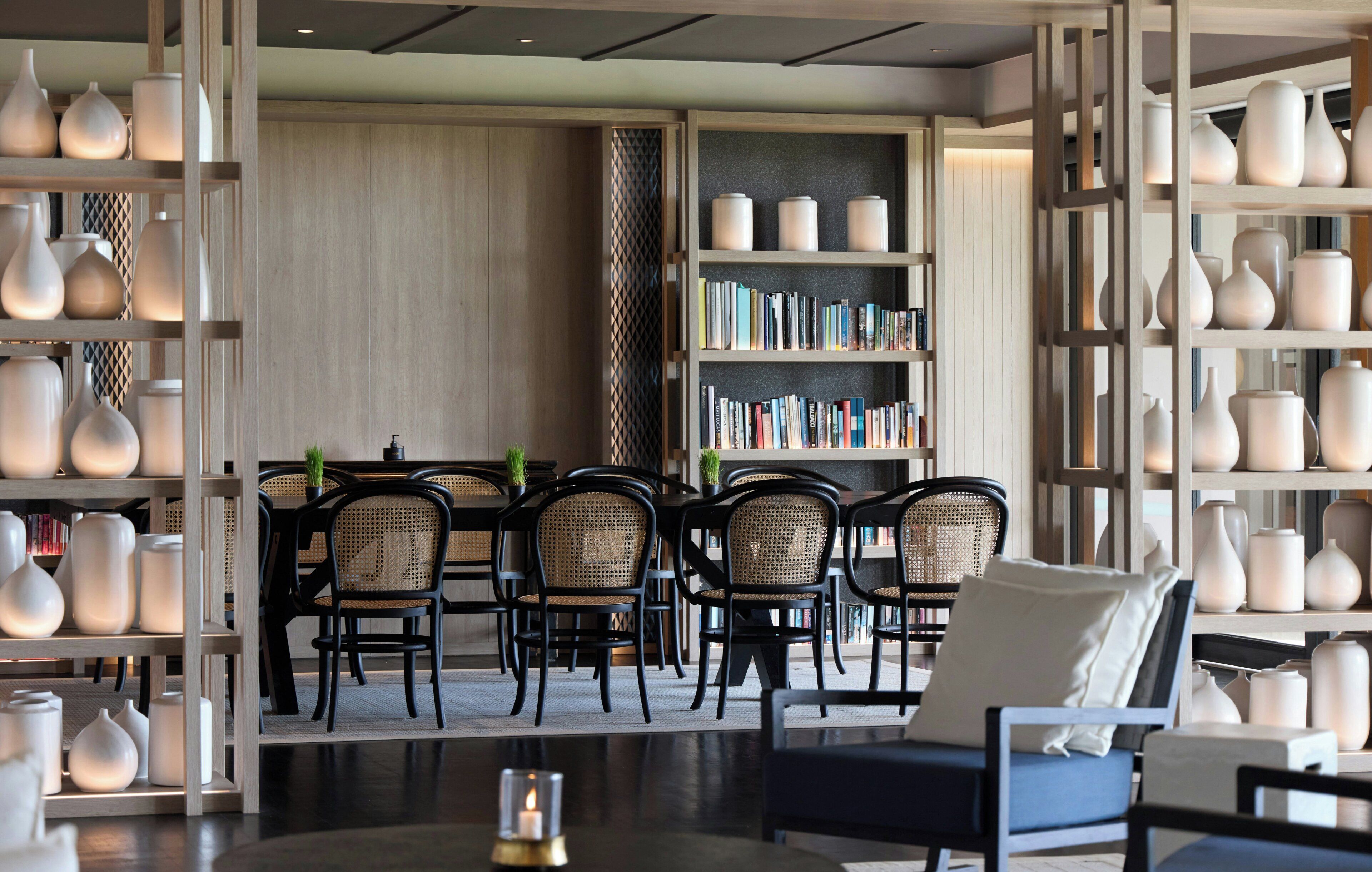 A modern interior with a dining area, bookshelves, and decorative vases.