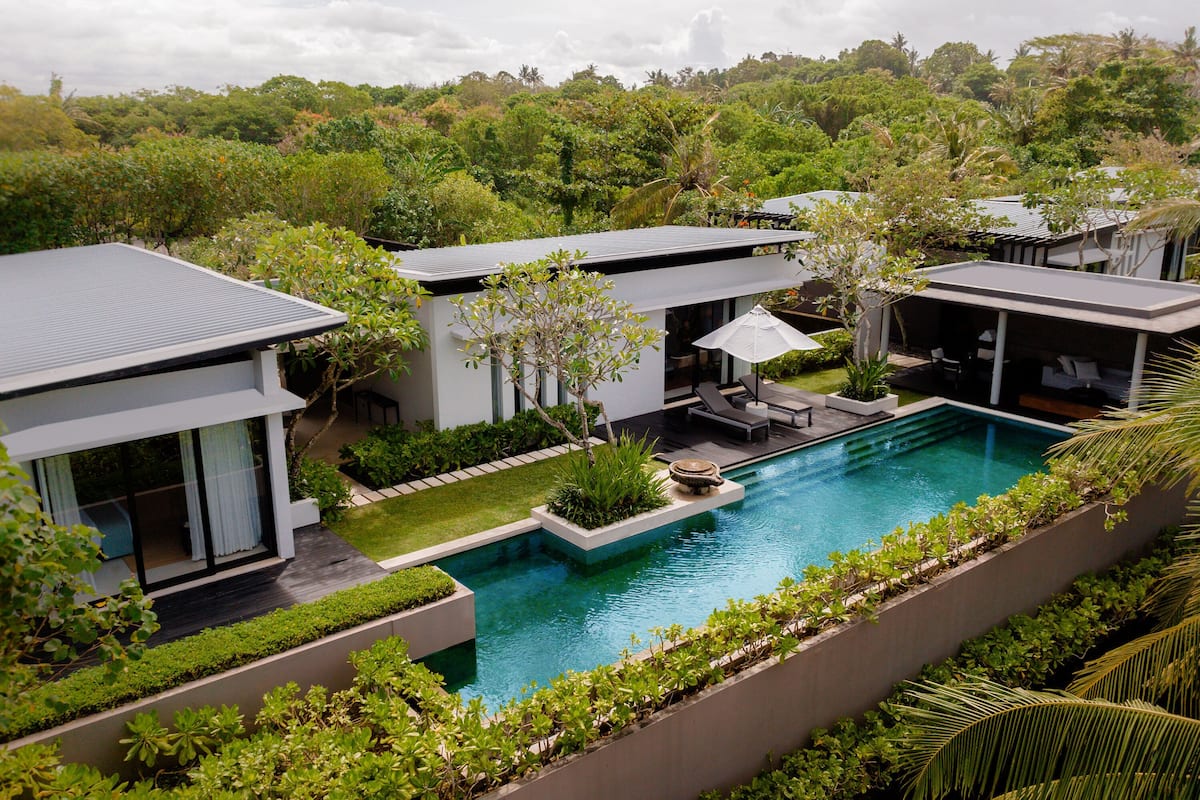 A modern resort with a swimming pool, outdoor seating, and lush greenery.