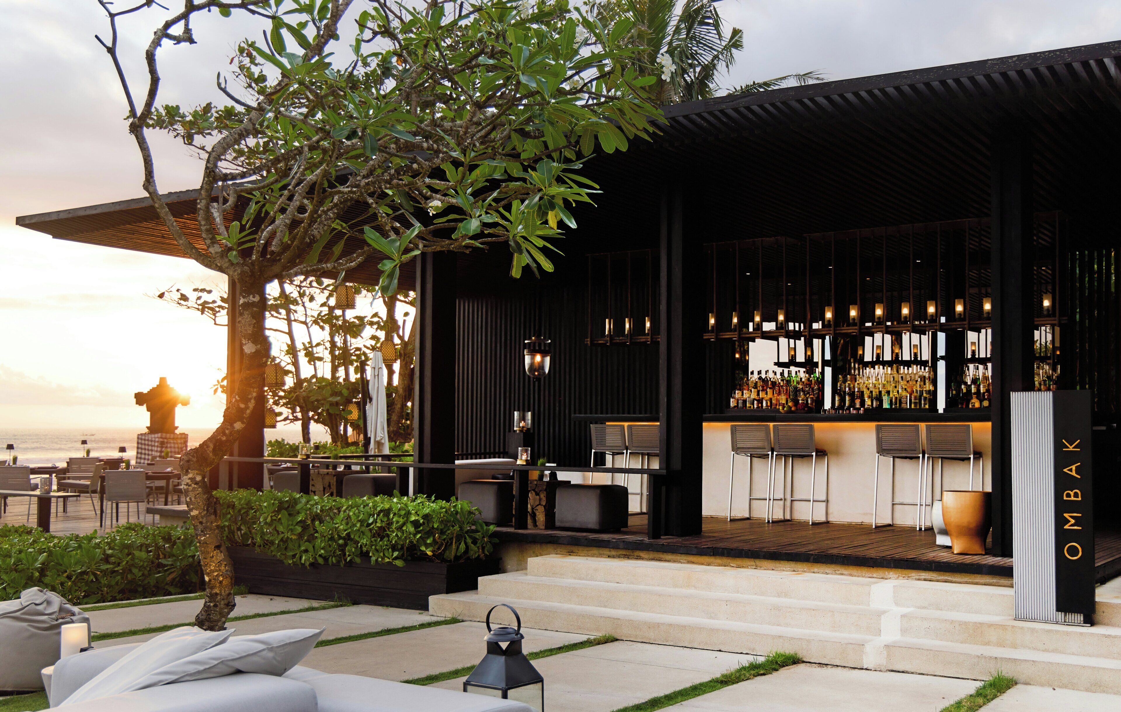 Un área de bar moderna al aire libre con asientos y vista al océano.
