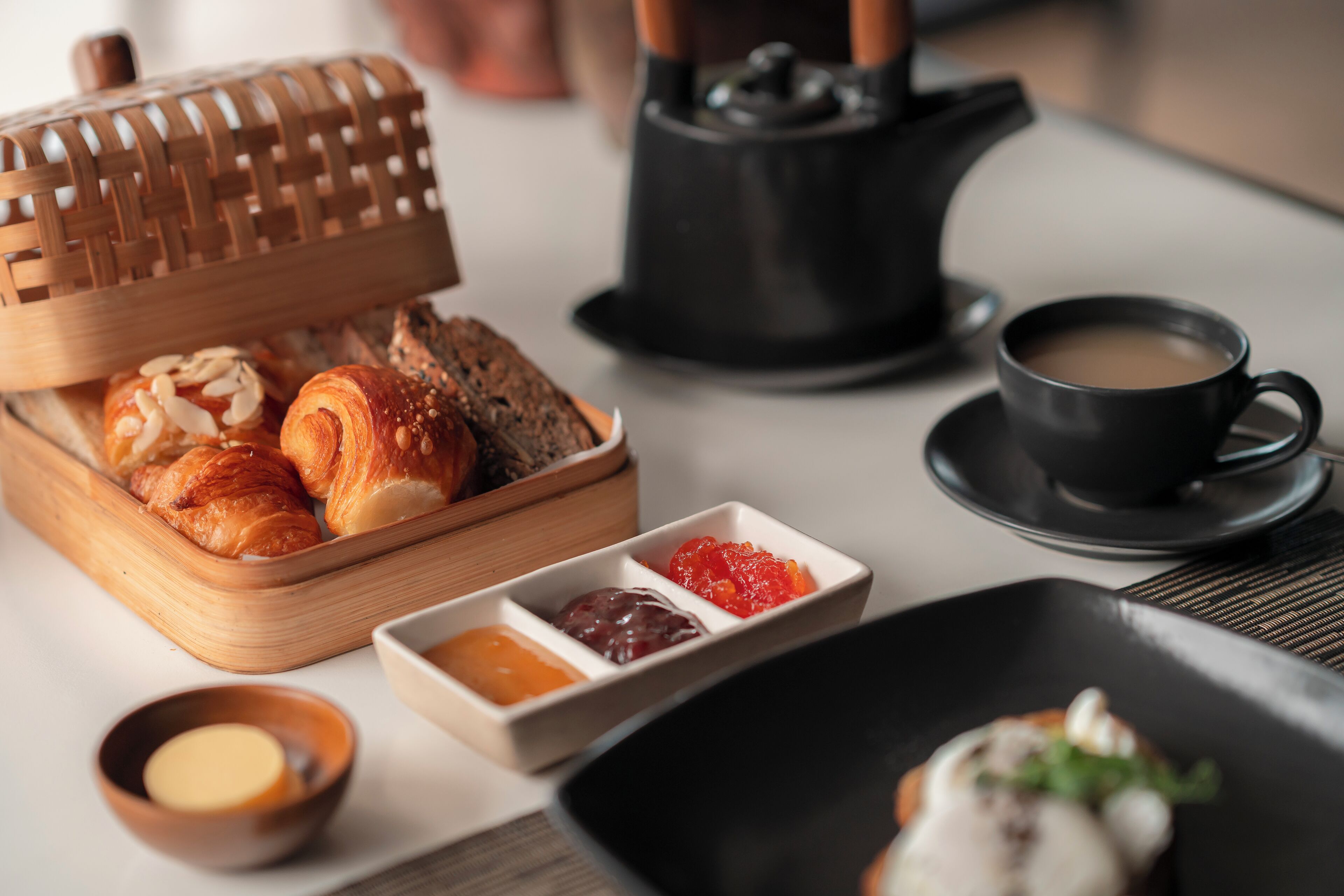 A breakfast setting with croissants, jams, and coffee.