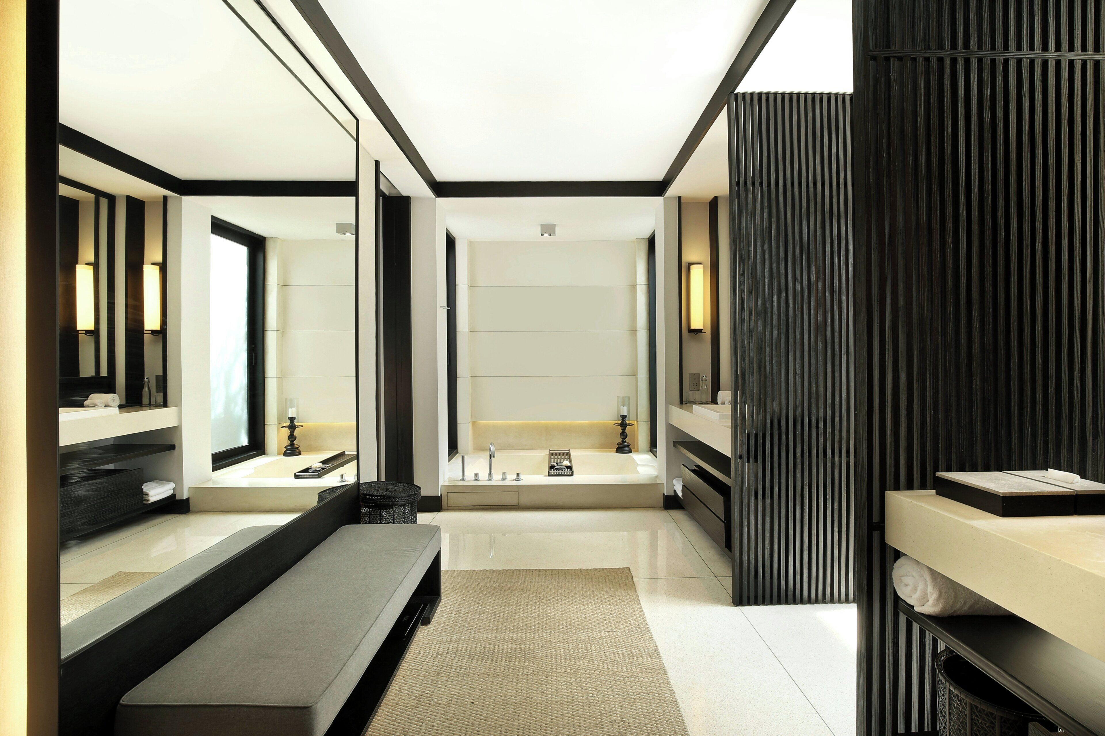 A modern bathroom with a large mirror, a bathtub, and a vanity with a sink.