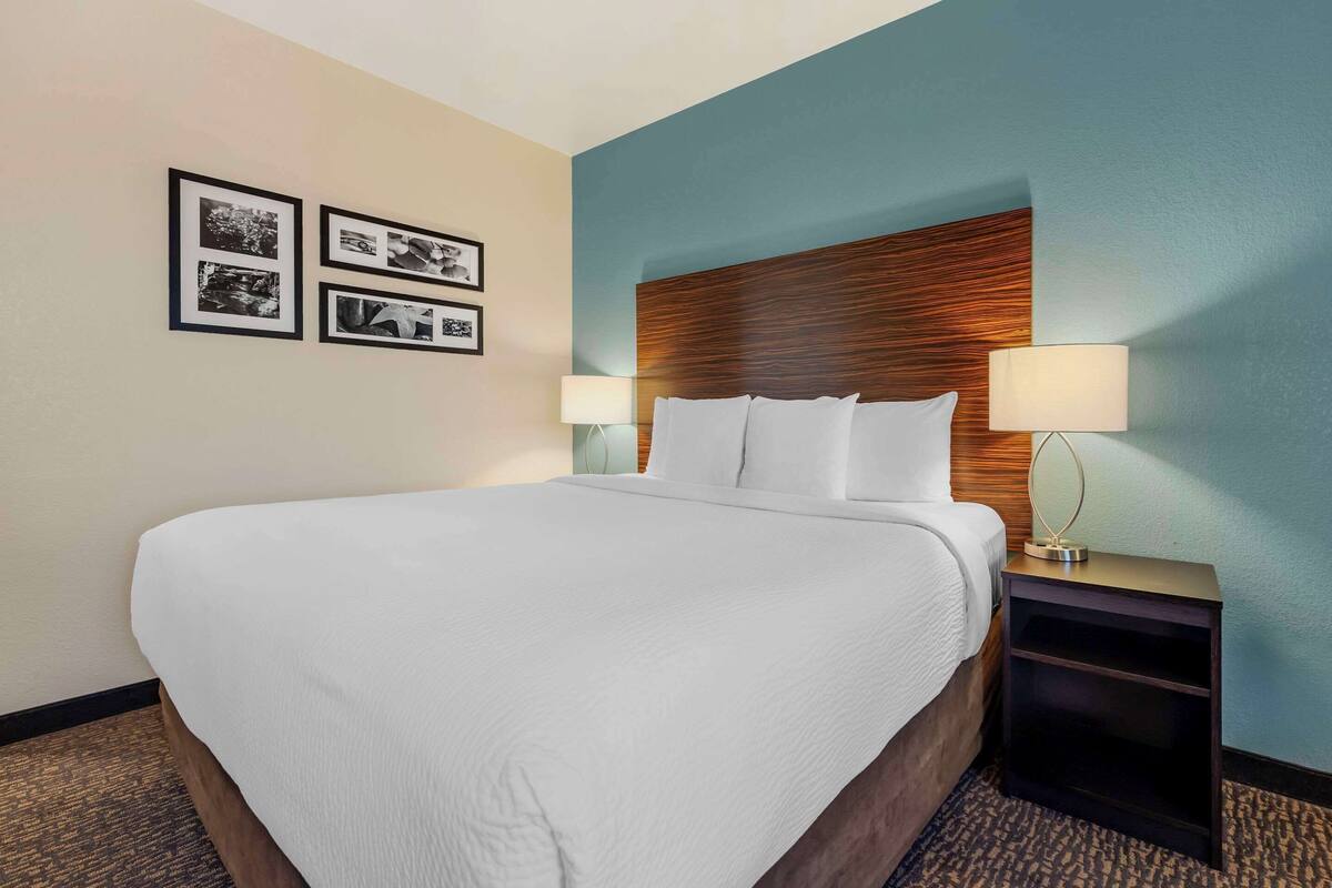 A hotel room with a large bed, two bedside tables with lamps, and a wall with framed pictures.