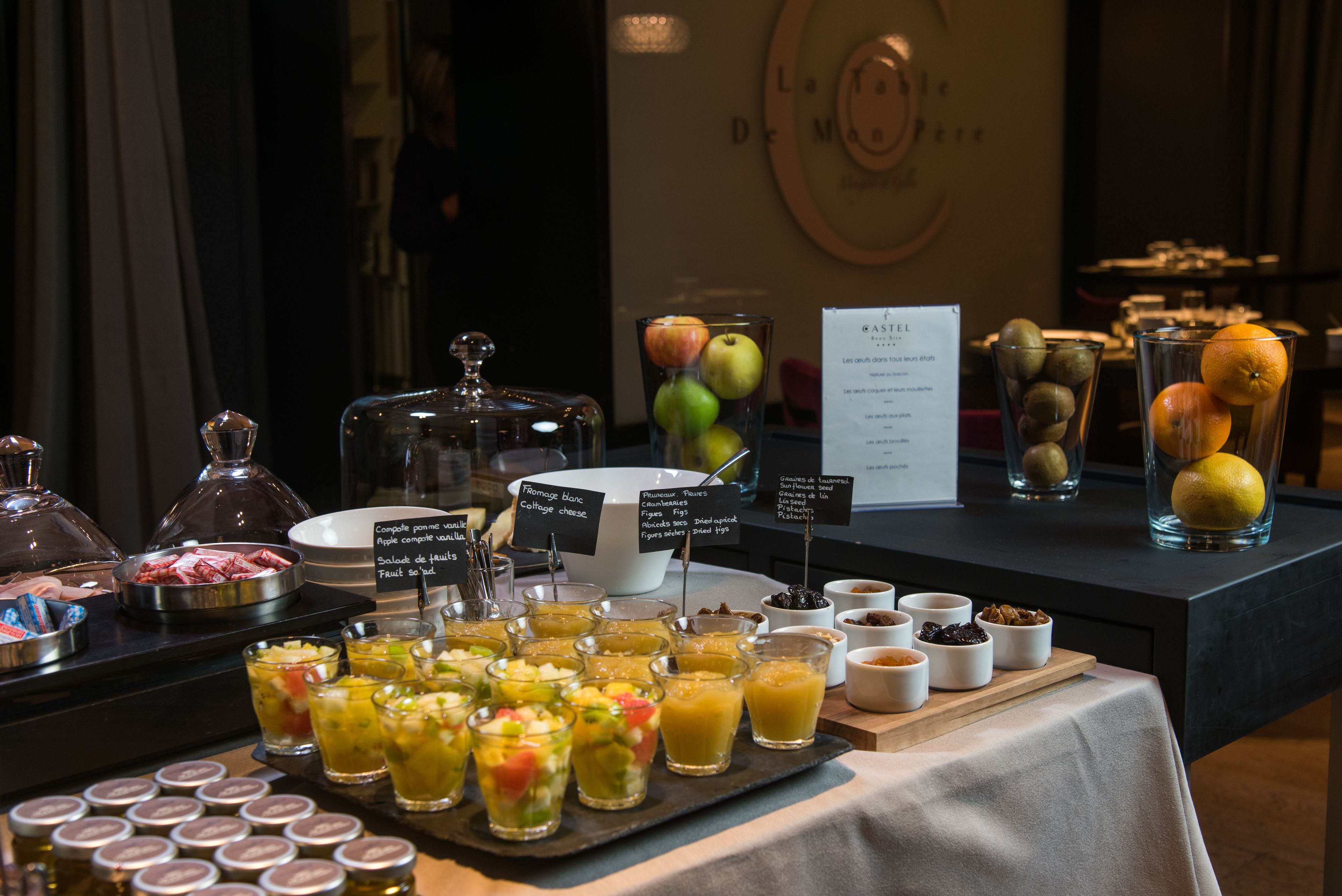 Un bufé con diversas opciones de comida y bebidas, entre ellas fruta, queso y jugos.