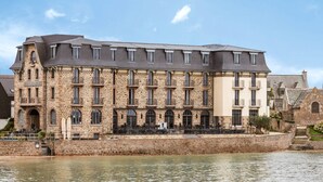 Un edificio de piedra con varios balcones y ubicación junto al río.