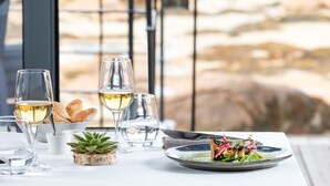 Una mesa con copas de vino, una planta pequeña y un plato de comida.
