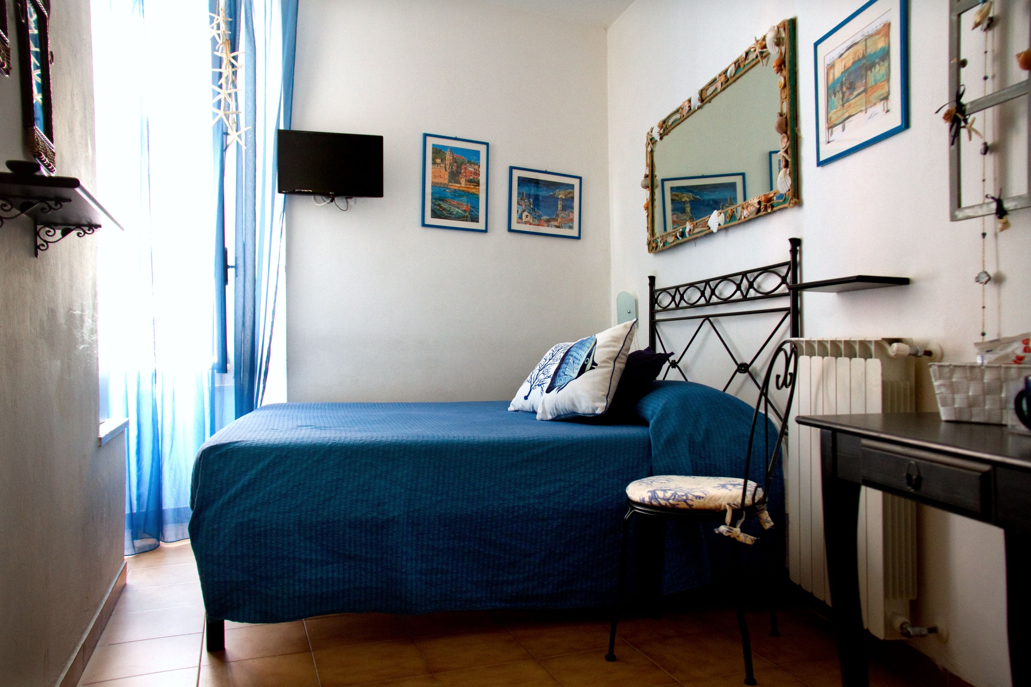 Une chambre à coucher comprenant un lit, une chaise, une commode, un miroir et deux tableaux encadrés accrochés au mur.