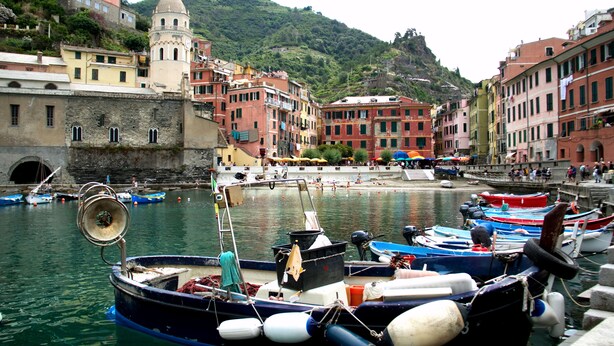 A harbor with boats docked, a historic building with a dome, and colorful buildings along the waterfront. - Rollando Affittacamere (Vernazza)