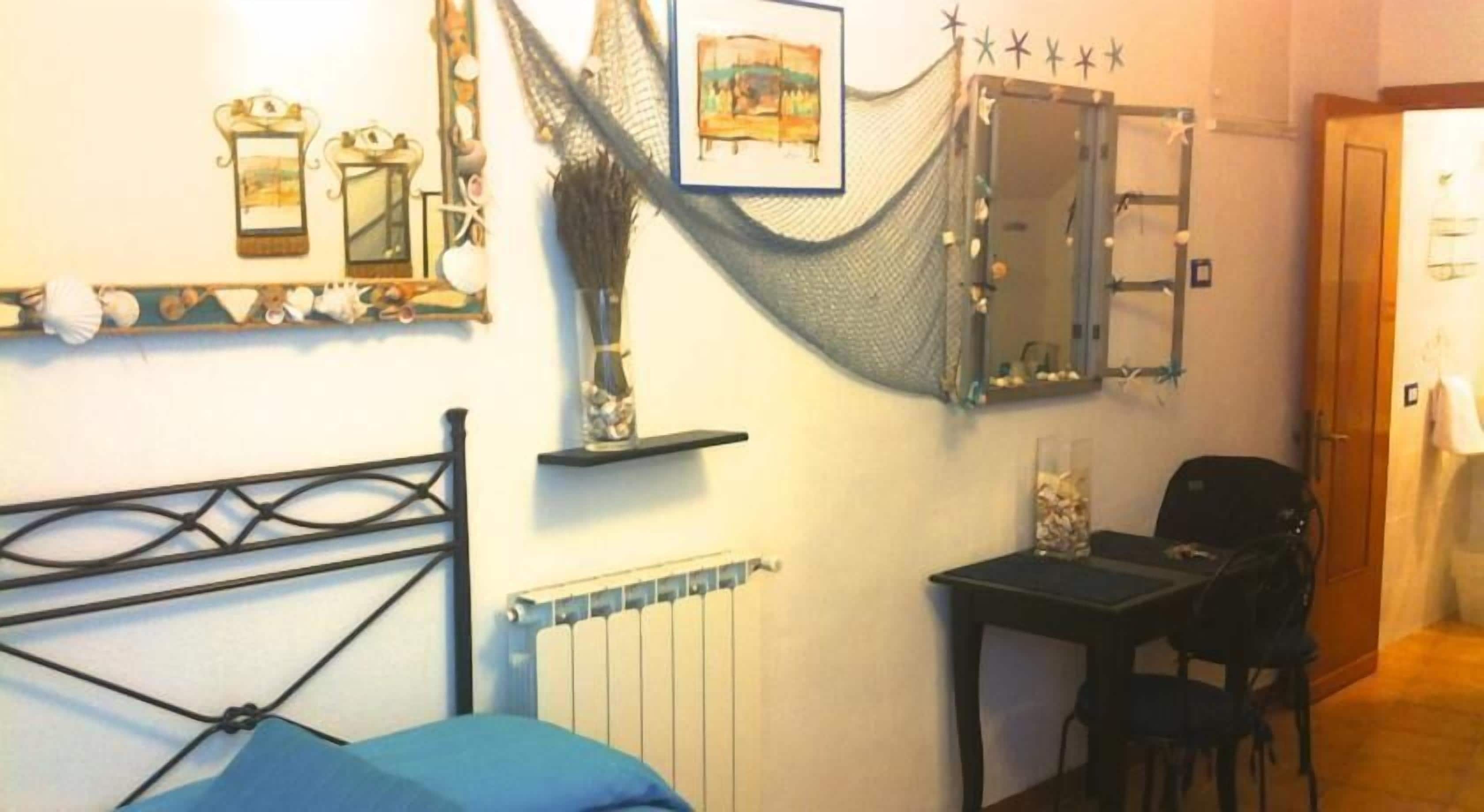 A bedroom with a bed, a desk, a chair, a radiator, and a mirror.