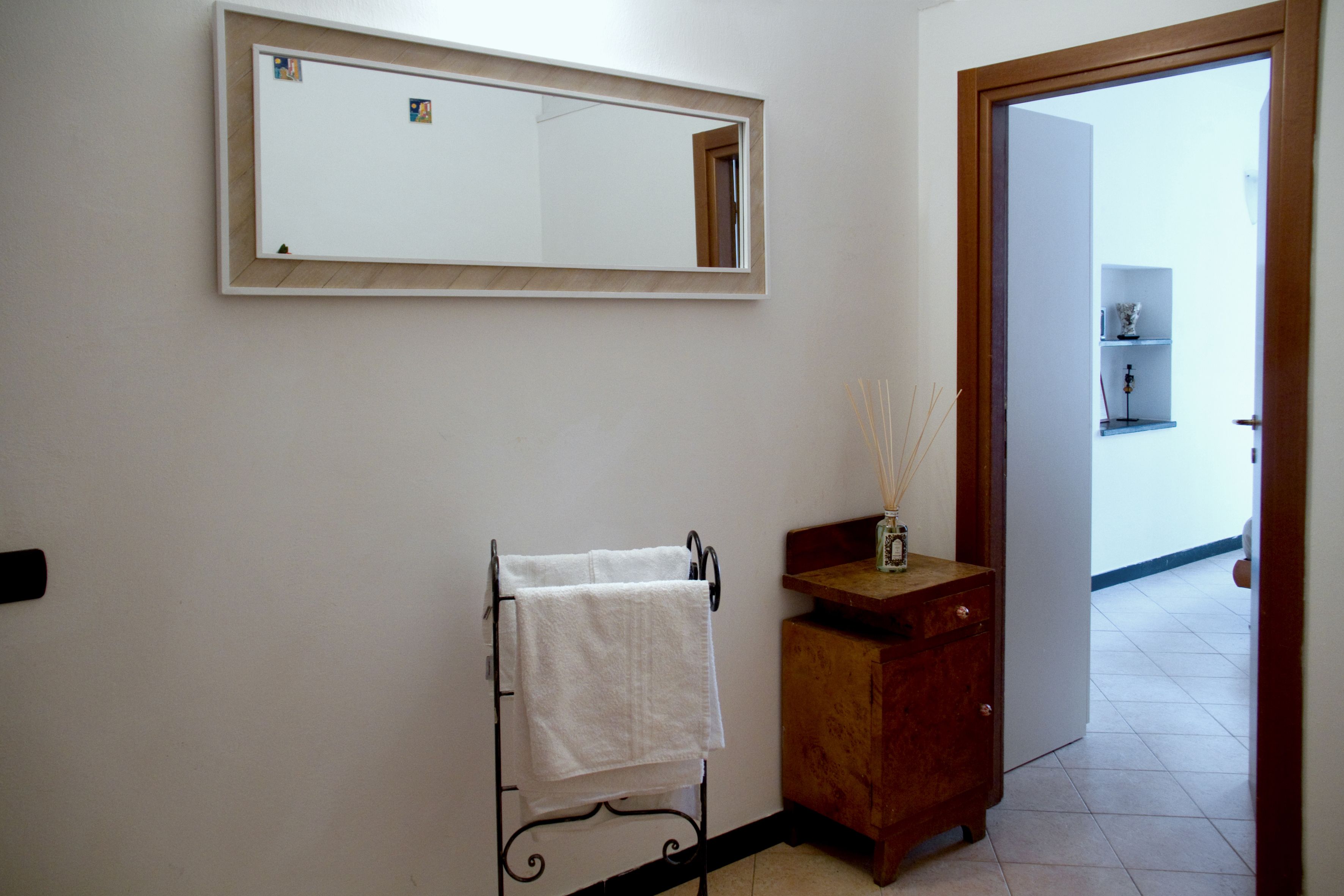 Un baño con pared blanca, un mueble de madera, un perchero metálico y un espejo.