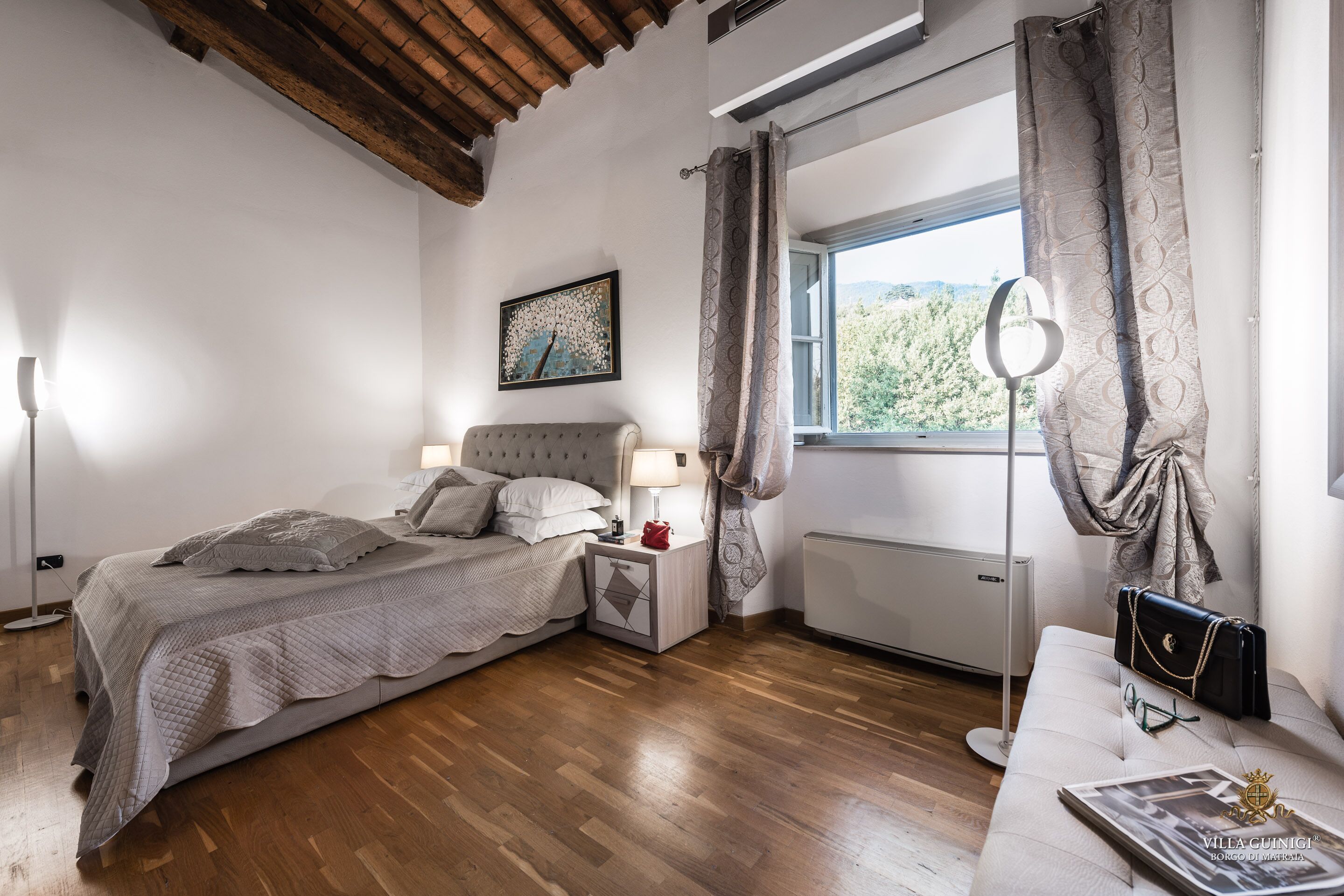 A bedroom with a bed, bedside table, lamp, and a window with curtains.