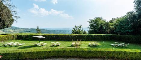 A well-manicured garden with neatly arranged outdoor seating and a clear view of the surrounding landscape.