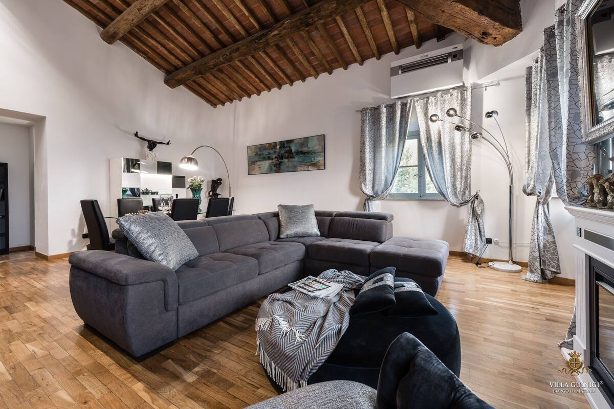 A modern living room with a large sectional sofa, a coffee table, and a fireplace.