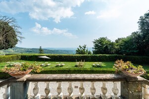 Una terraza con vistas a un jardín cuidado y colinas lejanas.