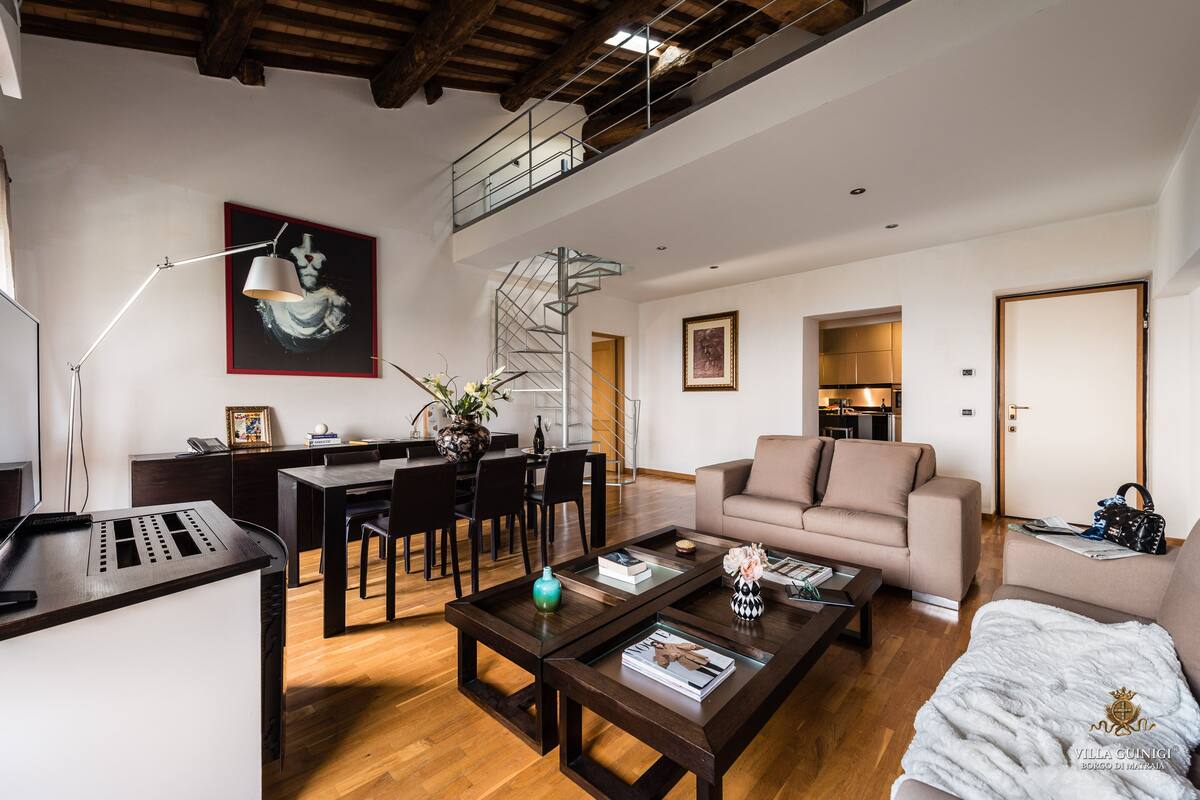 A spacious living area with a dining table, sofa, and staircase.