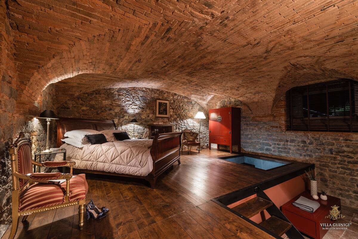 A bedroom with a stone wall, wooden bed, and a small pool.