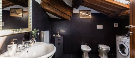 Een badkamer met een wastafel, bidet, toilet en wasmachine.