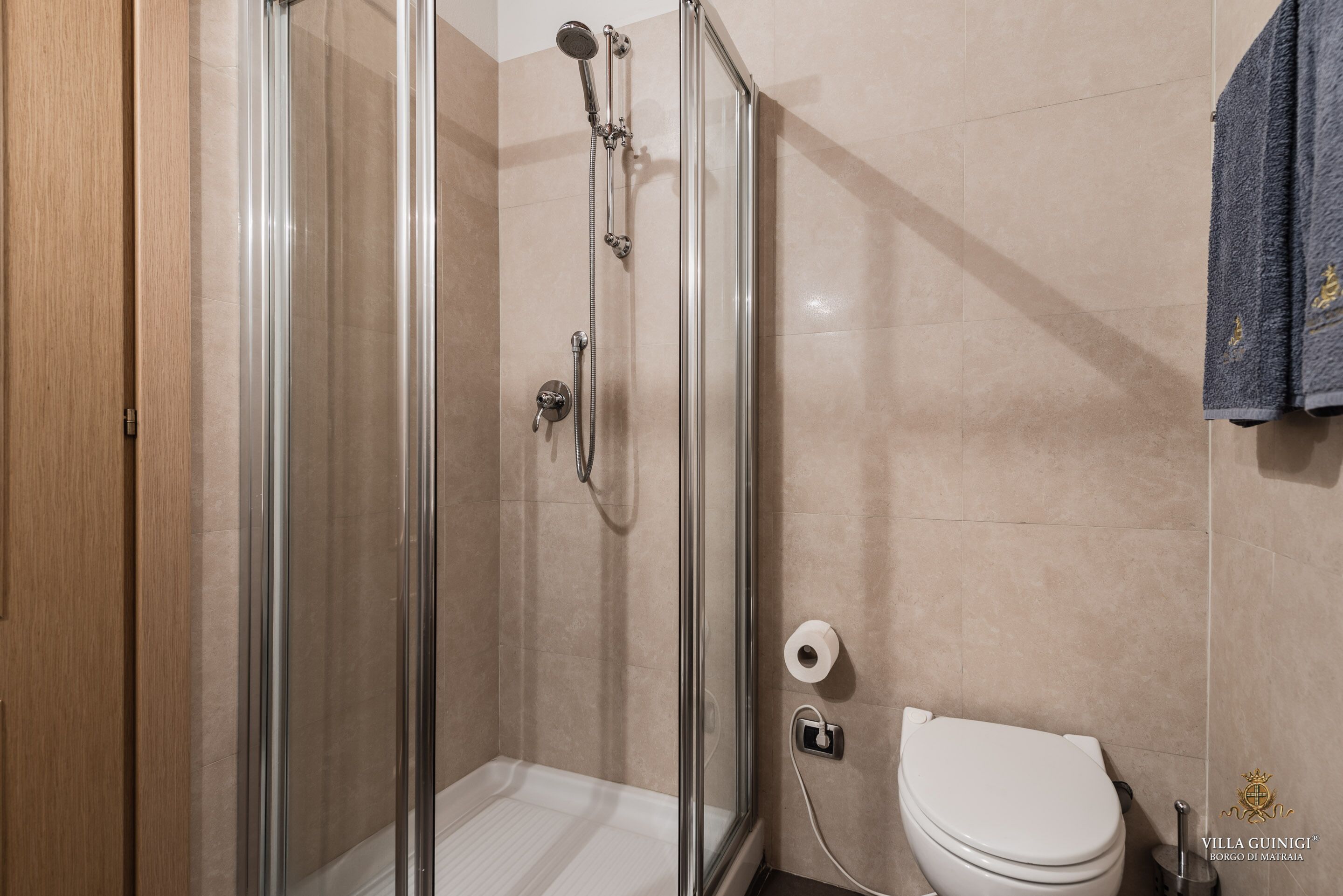 A modern bathroom with a glass-enclosed shower, a toilet, and a towel rack.