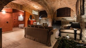 A cozy, brick-walled living room with a sofa, armchairs, and a TV.