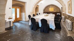 A dining room with a long table set for a meal, stone walls, and an arched ceiling.