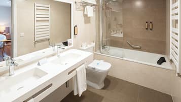 Een moderne badkamer met een wastafel met dubbele wastafel, een toilet, een douche met glazen wand en een bad.
