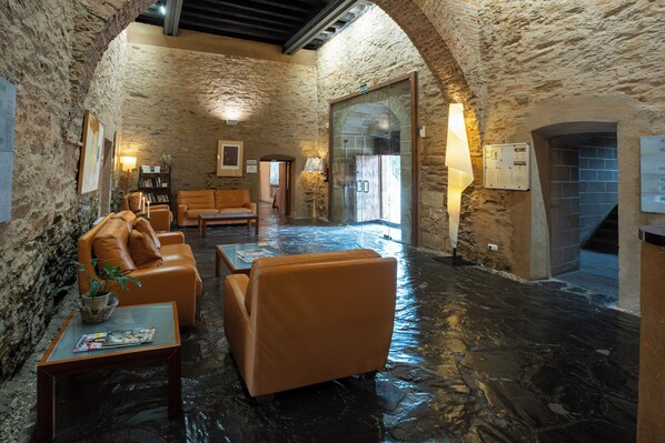 Una habitación con paredes de piedra, sofás de cuero, una mesa de centro y una lámpara.
