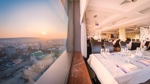 A restaurant with a table set for dining, a view of the cityscape, and a modern interior design.