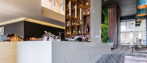 A modern reception area with a marble counter, a wine and liquor display, and a patterned carpet.