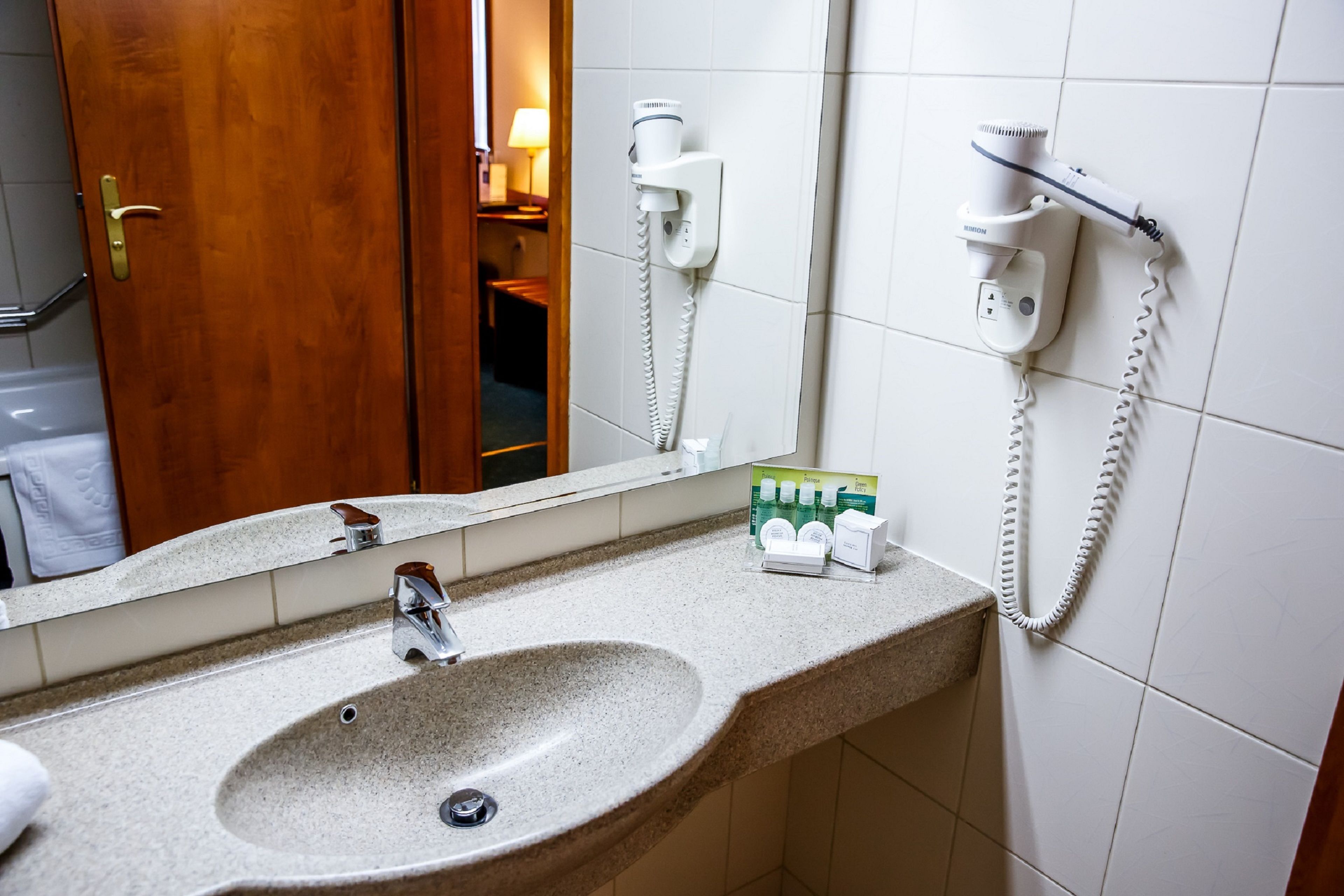 A bathroom with a sink, a mirror, a hairdryer, and a towel rack.