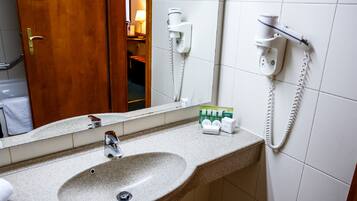 A bathroom with a sink, a mirror, a hairdryer, and a towel rack.
