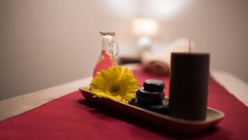 A tray with a yellow flower, a glass bottle, and black stones on a red cloth.
