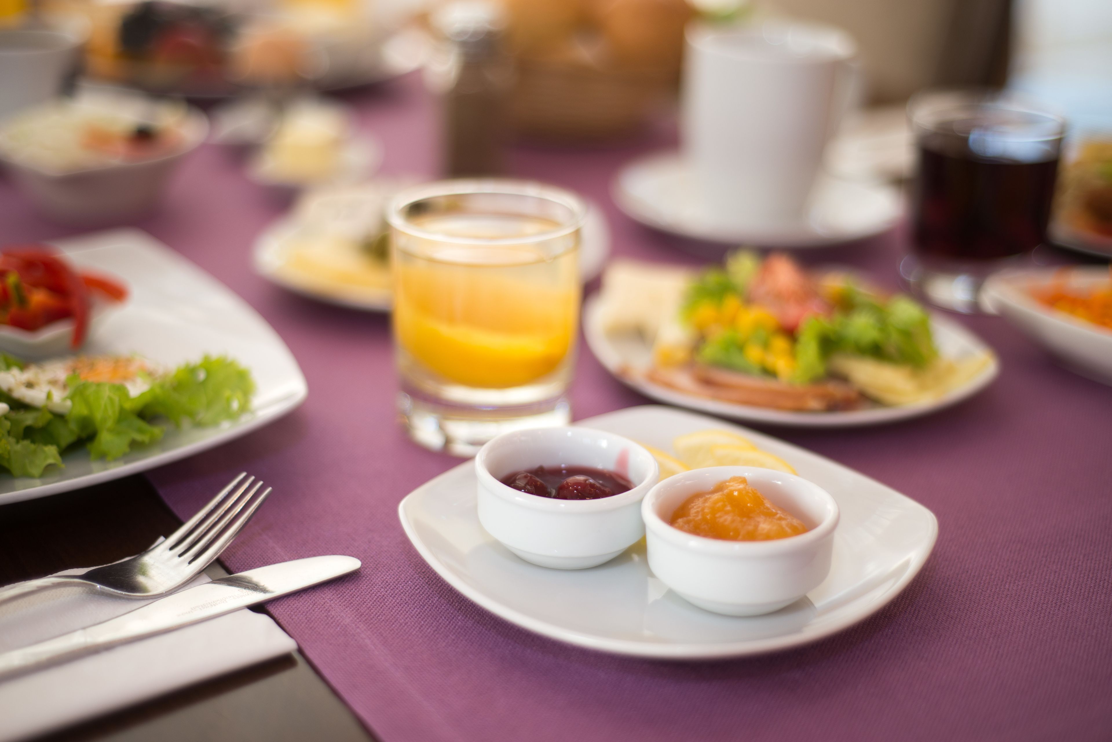 Een eettafel met borden eten, een glas sinaasappelsap en kleine schaaltjes met toevoegingen.
