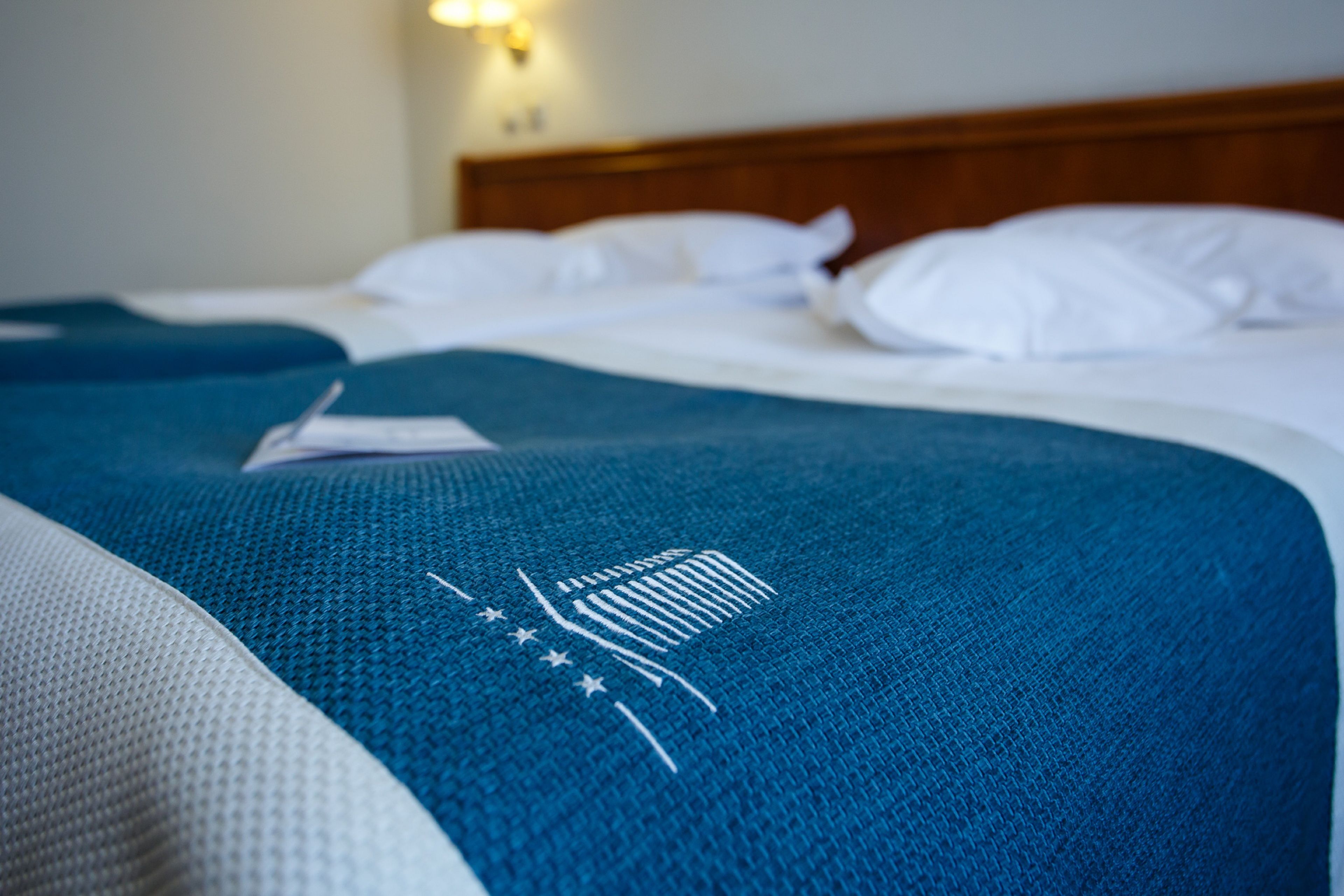 A bed with a blue blanket and white pillows.