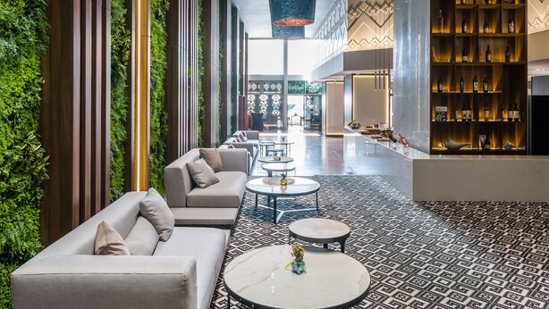 A modern lounge area with sofas, round tables, and a patterned floor.