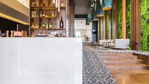 A modern lobby with a marble reception desk, a patterned carpet, and a green wall with vertical gardens.