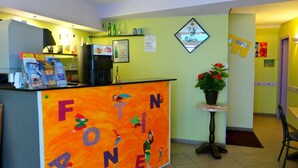 A reception area with a colorful 'FON' sign, a coffee machine, and a small plant. - Hôtel La Fontaine (Lourdes)