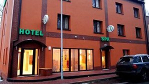Hotel met een bord waarop een spa wordt aangeduid en een auto ervoor geparkeerd.