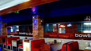 Een bowlingclub met rode zitplaatsen en houten details.