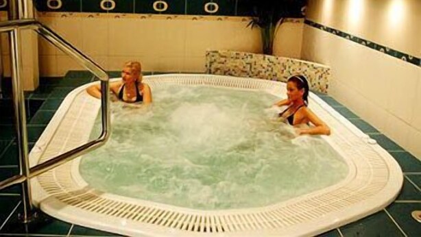 Een jacuzzi met twee personen, omringd door een betegelde muur met cirkelvormige patronen.