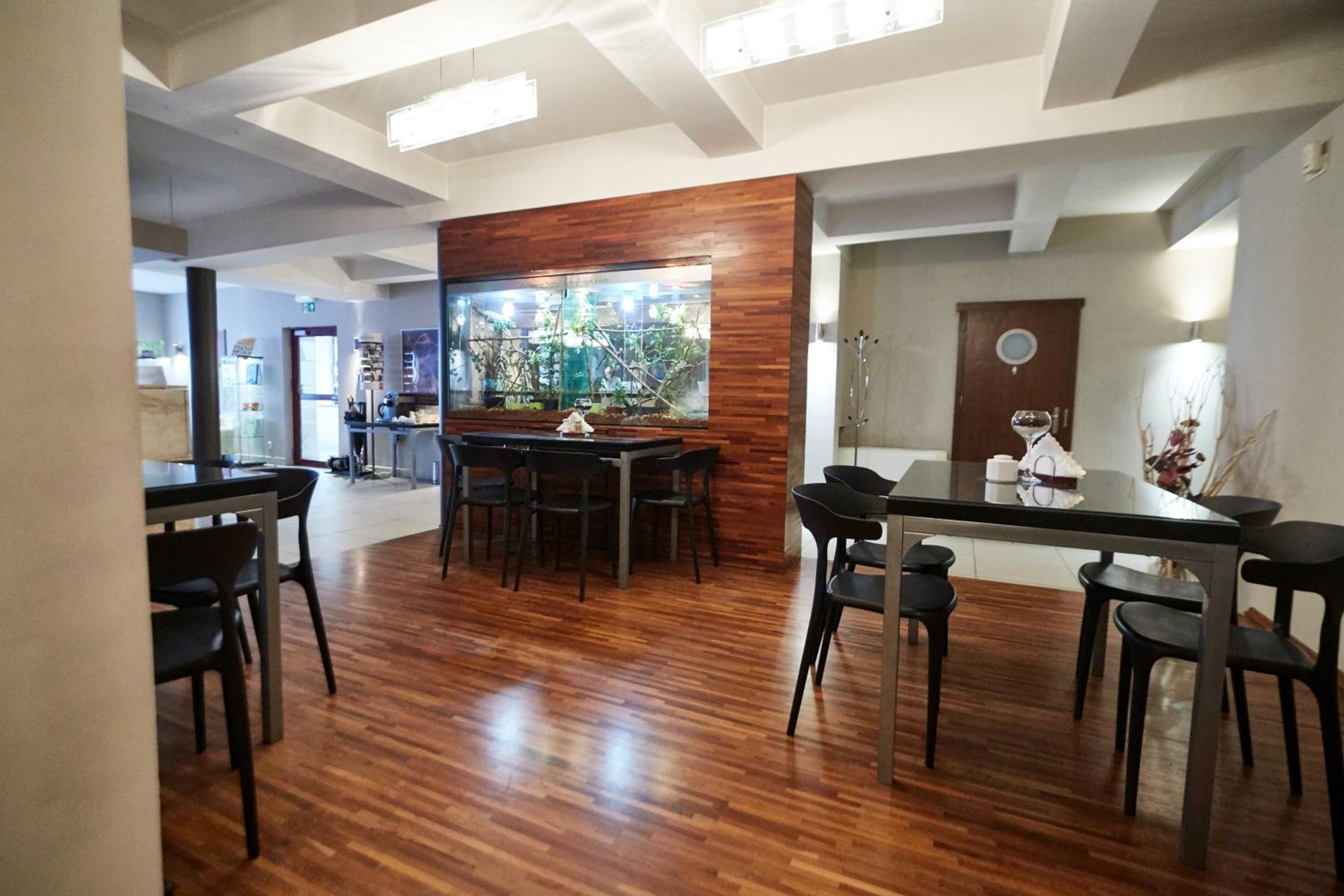 A modern dining area with a wooden accent wall, a large aquarium, and a bar with stools.