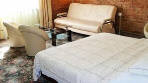 Een hotelkamer met een bakstenen muur, een bank, een stoel, een bed en een foto aan de wand.