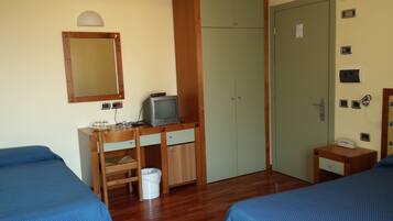 A hotel room with two beds, a wooden desk with a television, a mirror, and a wardrobe.