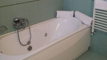 Ein Badezimmer mit einer weißen Badewanne, einer Duschbrause und einem Handtuchhalter.