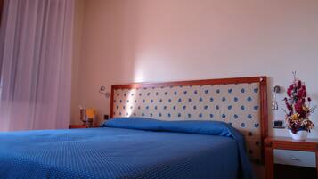 Ein Hotelzimmer mit Bett, Nachttisch, Lampe und einer Blumenvase.