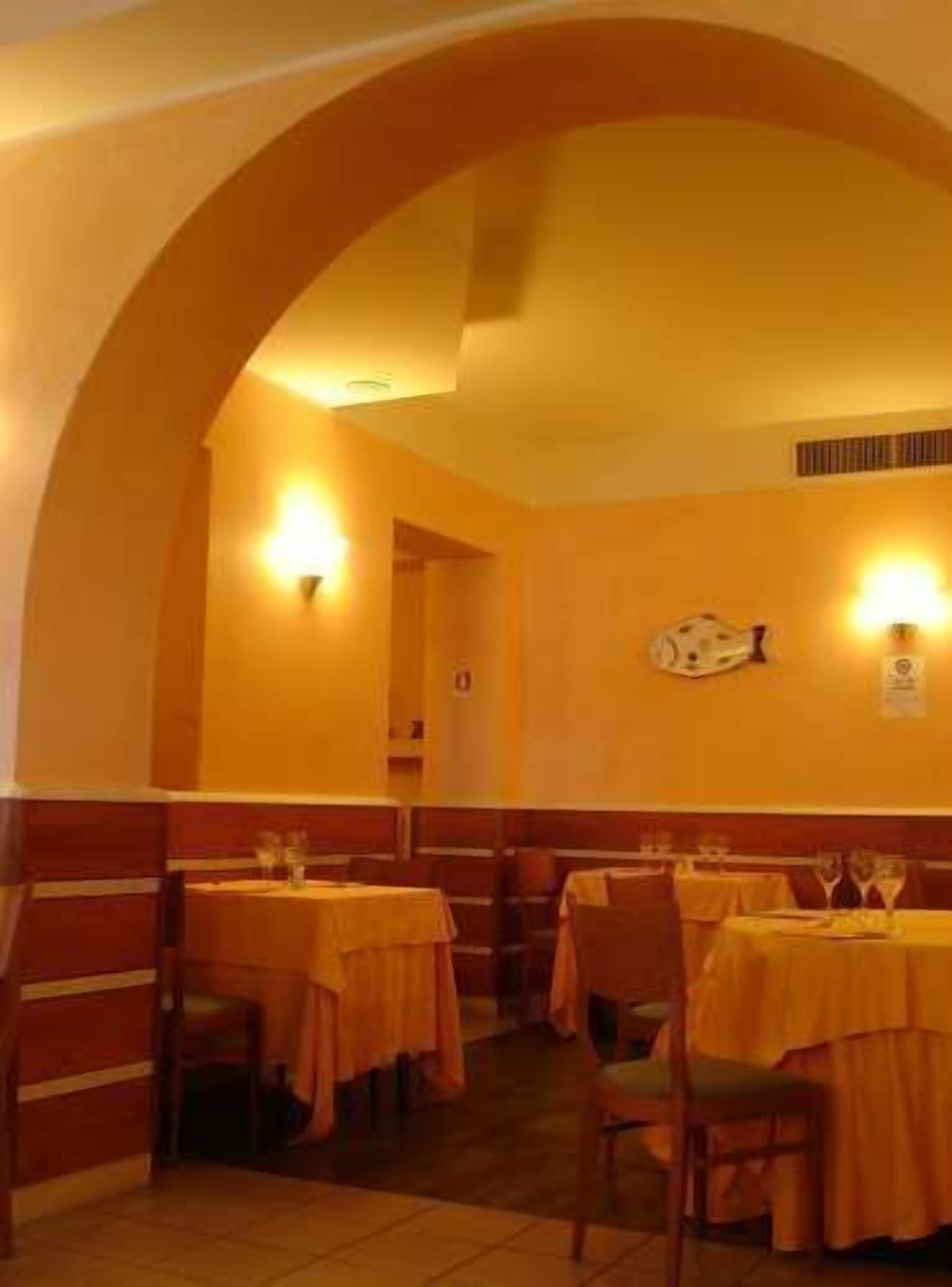 Ein Restaurant mit Tischen, die mit gelben Tischdecken bedeckt sind, Holzkabinen und Wandleuchten.