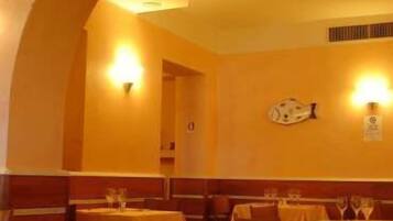 Ein Restaurant mit Tischen, die mit gelben Tischdecken bedeckt sind, Holzkabinen und Wandleuchten.
